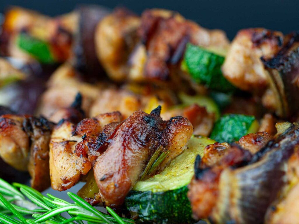 Closeup of a chicken kebab with roasted vegetables.