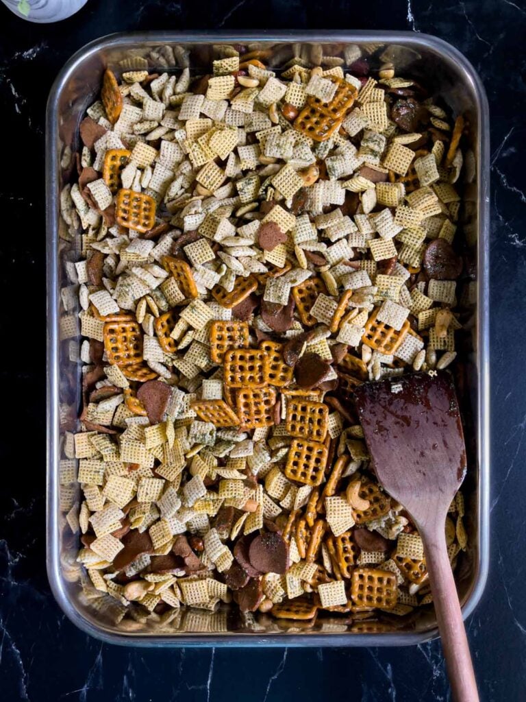 Unbaked Dill Pickle Chex mix combined with seasonings in a large baking pan.