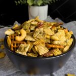 Dill Pickle Chex Mix in a small dark bowl on a light linen napkin.