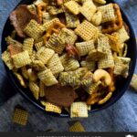 Dill Pickle Chex Mix in a dark bowl on a light linen napkin.