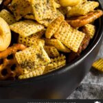 Dill Pickle Chex Mix in a dark bowl on a light linen napkin.