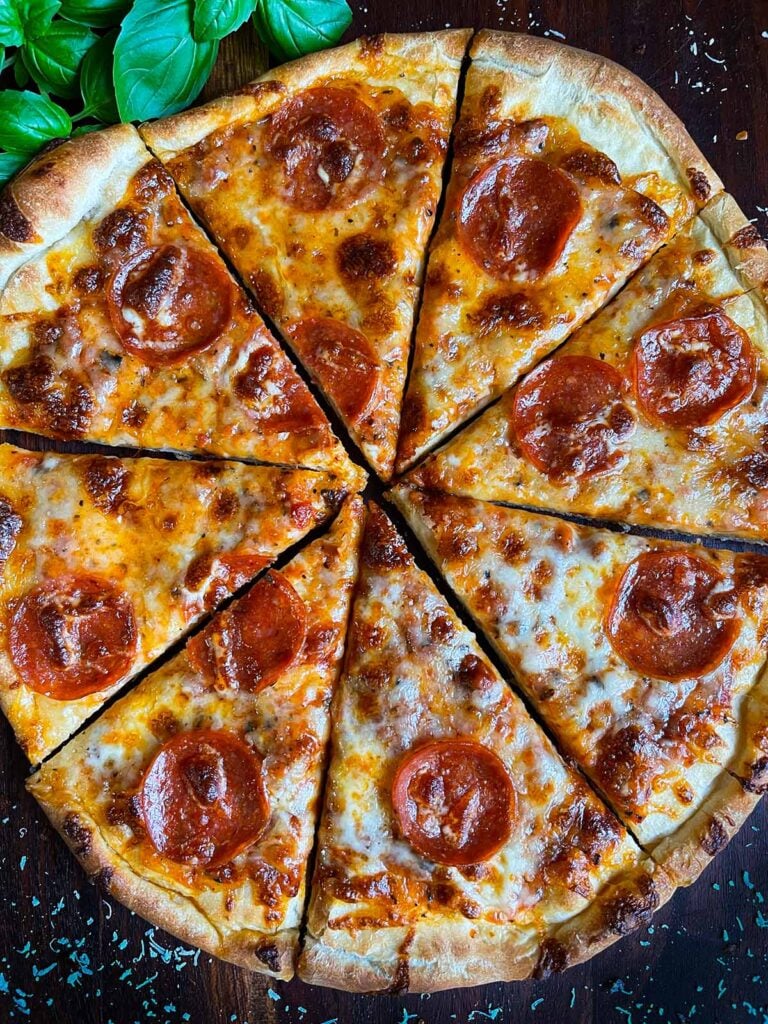 A homemade pepperoni pizza right out of the oven, sliced.