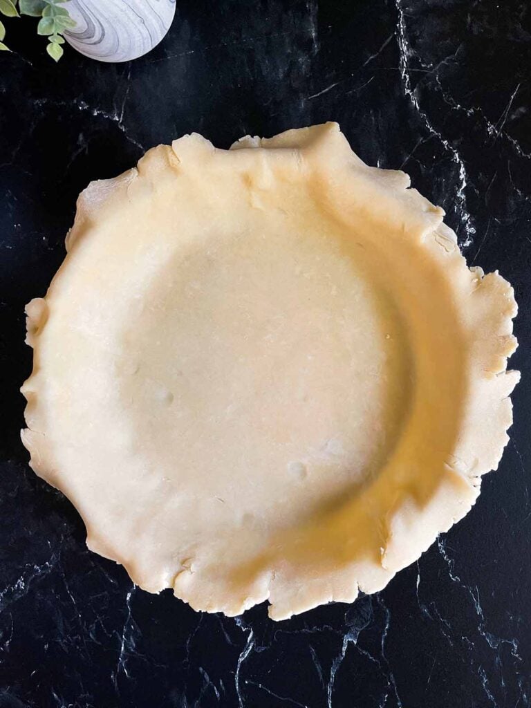 A raw pie crust in a pie baking dish.
