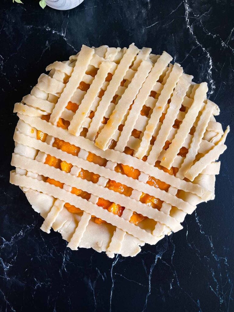 A peach pie with a lattice crust being applied.