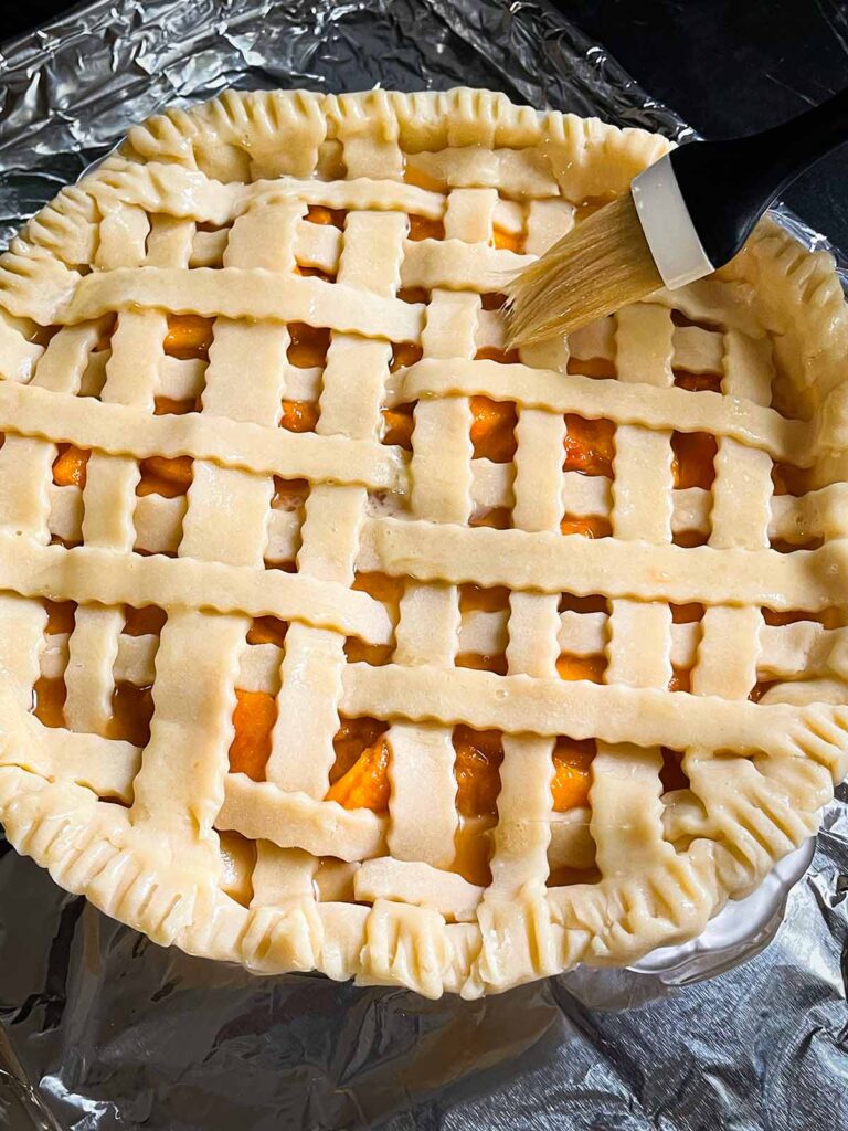 Applying an egg wash to a lattice pie crust.