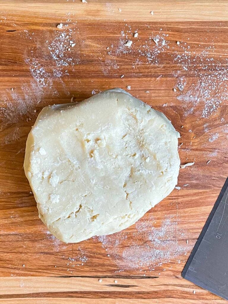 Pie crust dough on a wooden cutting board.