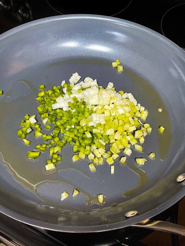 Onions, celery, and green bell pepper with olive oil in a skillet.