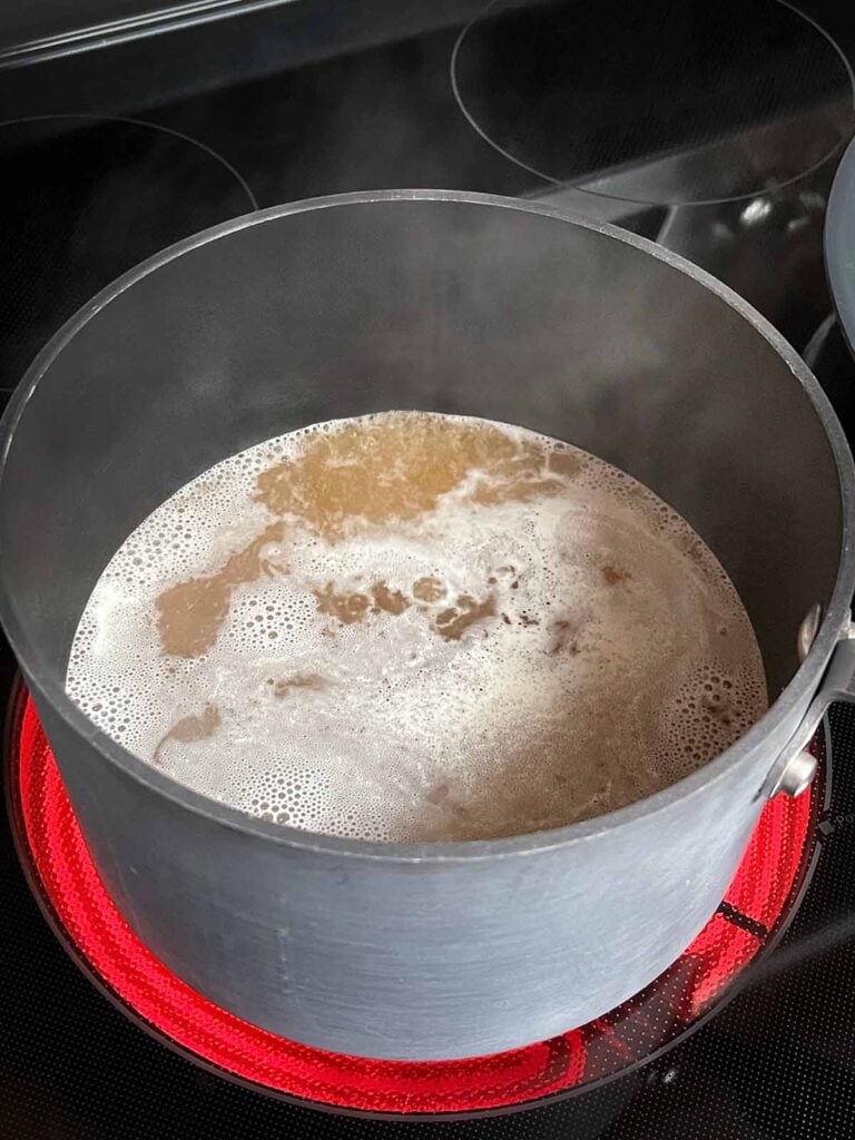Chicken stock boiling in a sauce pan.
