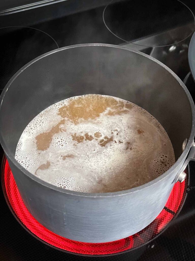 Chicken stock boiling in a sauce pan.