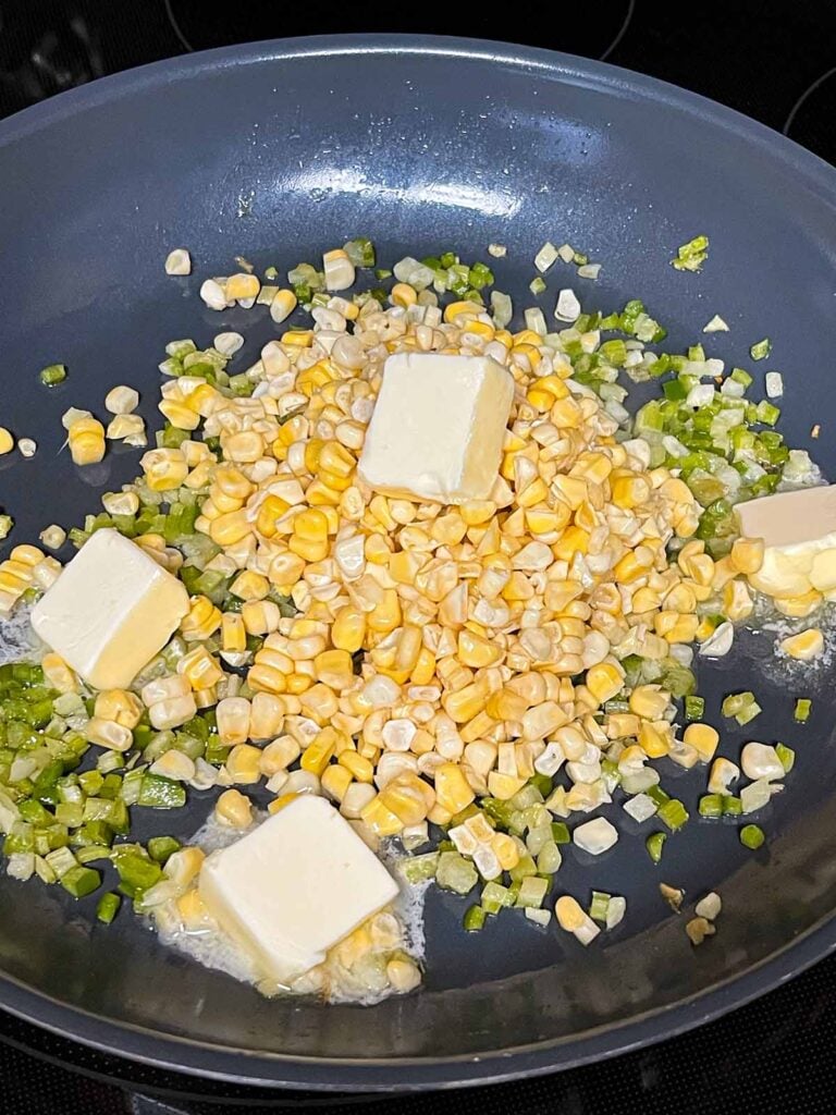 Butter and corn added to a skillet with the holy trinity.