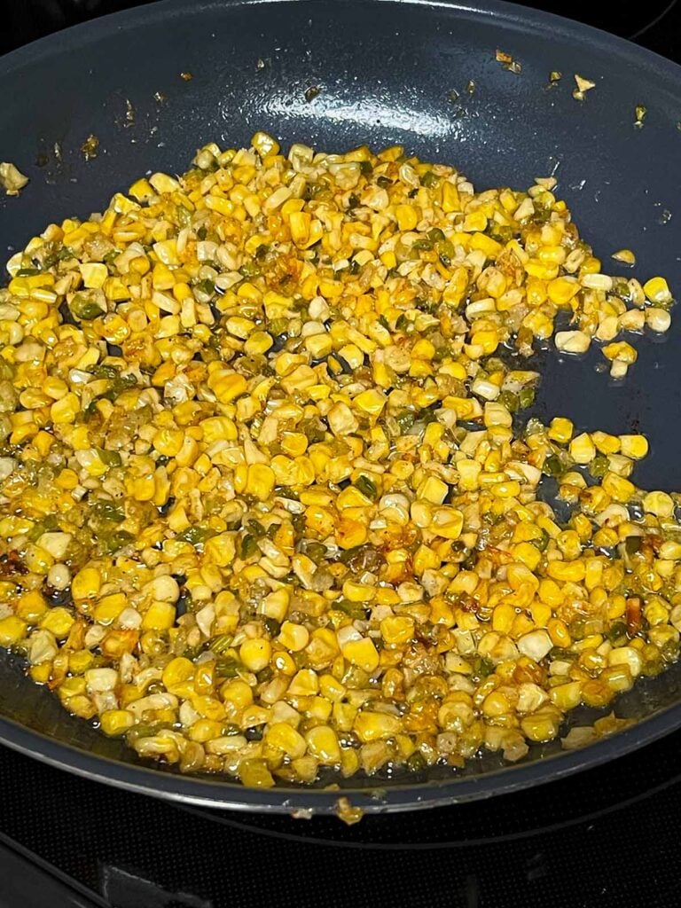 A butter corn and holy trinity mixture in a skillet.