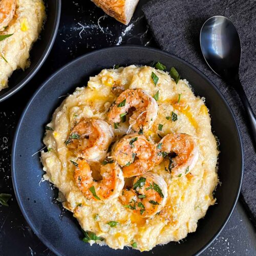 Spicy shrimp on a bed of Cajun polenta in a dark bowl.