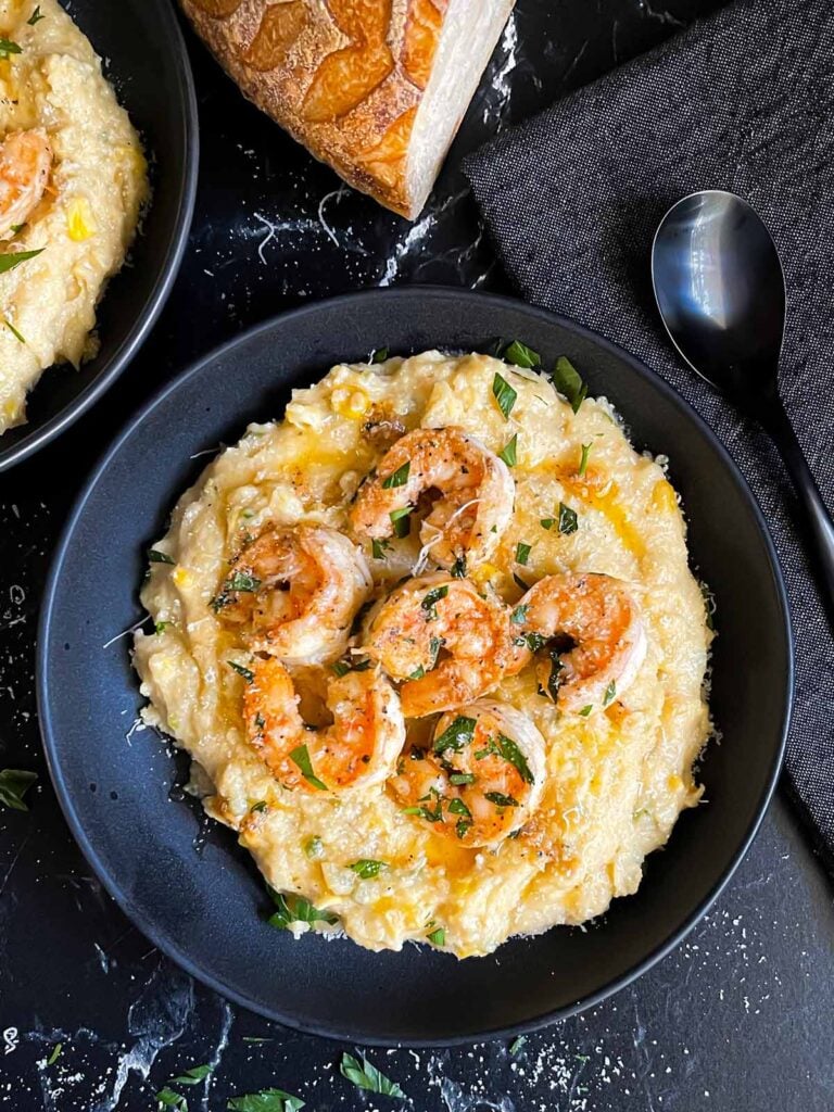 Spicy shrimp on a bed of Cajun polenta in a dark bowl.