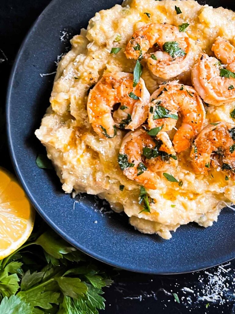 Spicy shrimp on a bed of Cajun polenta in a dark bowl.