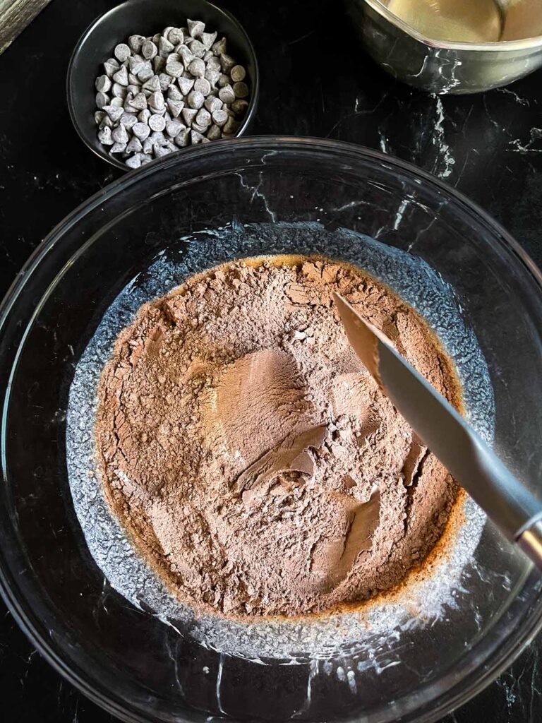 Ingredients in a large glass bowl for double chocolate muffins.