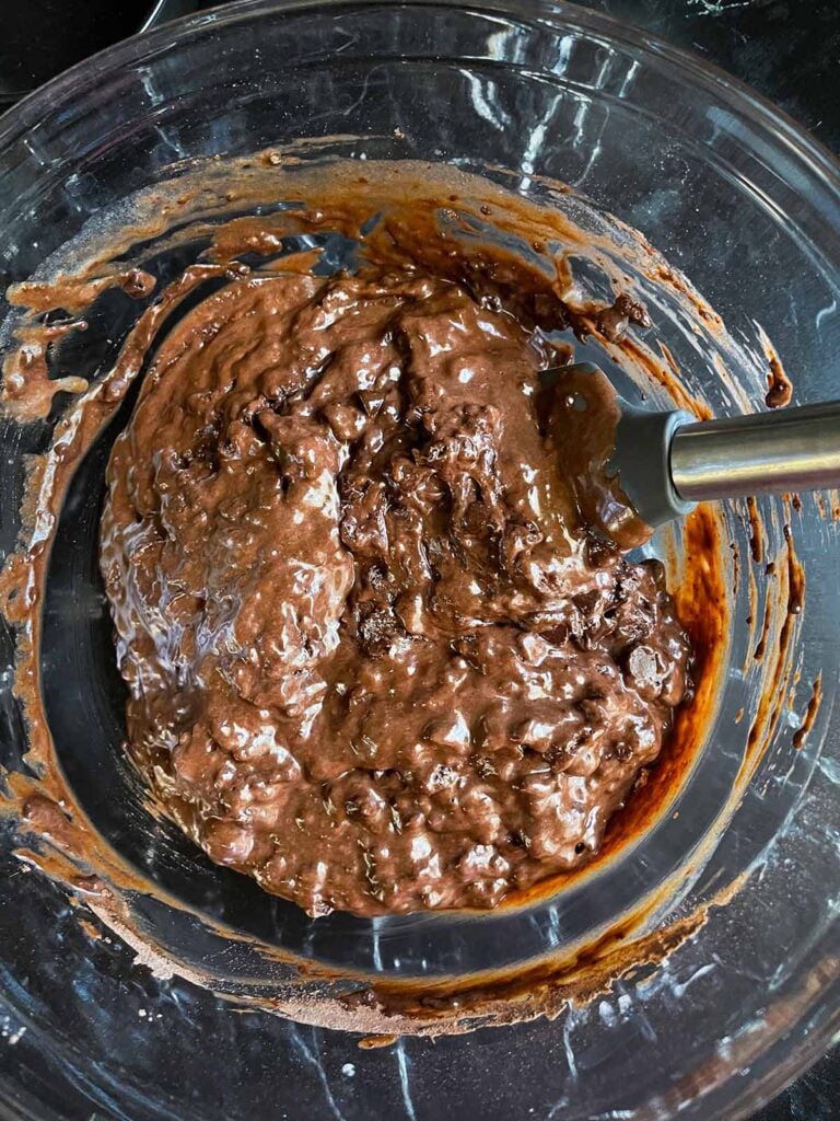 Mixing all the ingredients for double chocolate muffins in a large glass bowl.