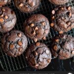 Double chocolate muffins on a wire rack on a dark surface.