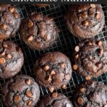 Double chocolate muffins on a wire rack on a dark surface.