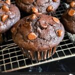 Double chocolate muffins on a wire rack on a dark surface.