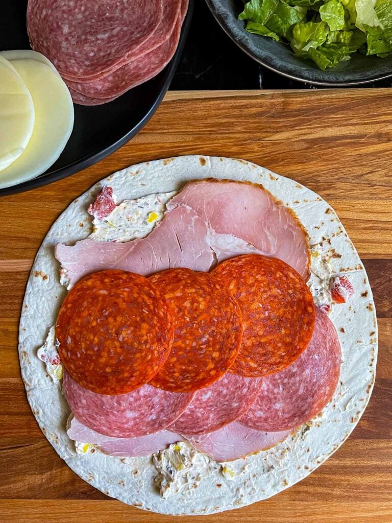 A layer of pepperoni on the italian pinwheel as it's being made.