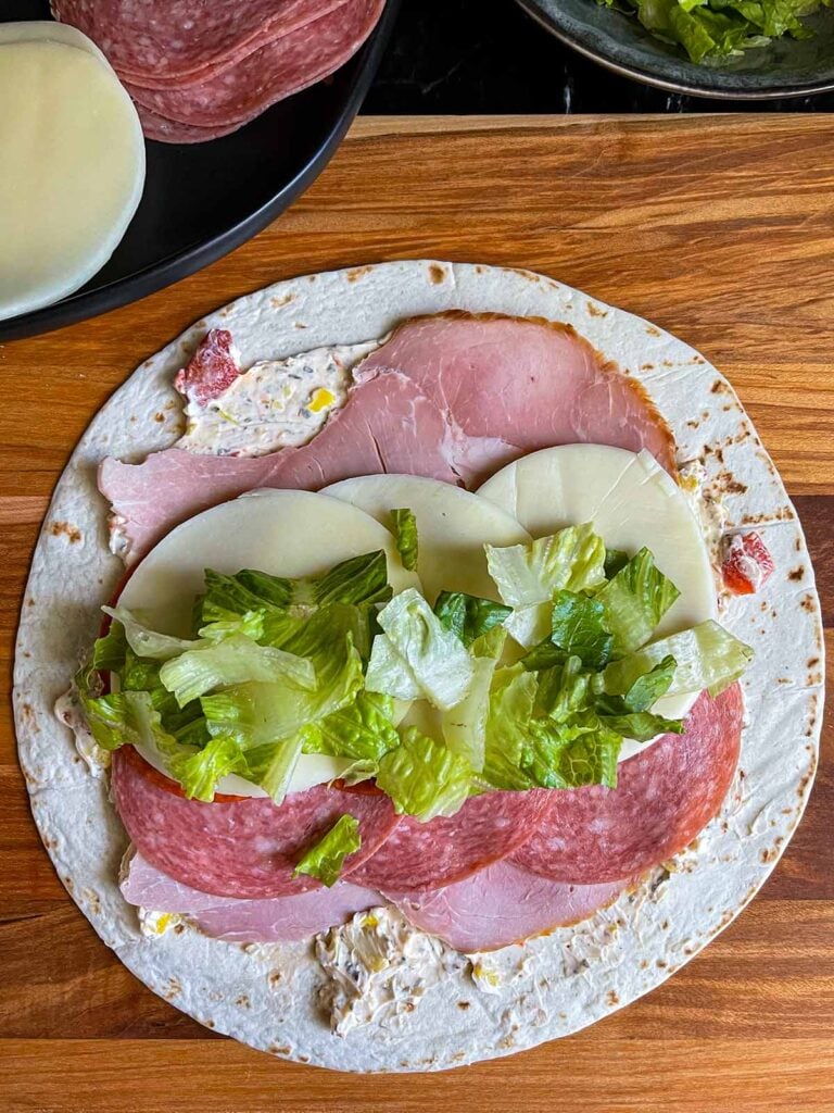 A layer of lettuce on the italian pinwheel as it's being made.