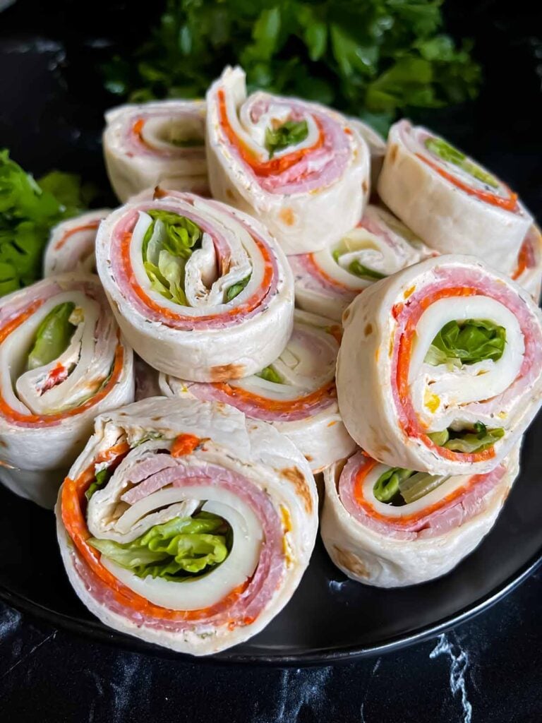 Italian pinwheels on a dark plate on a dark surface.