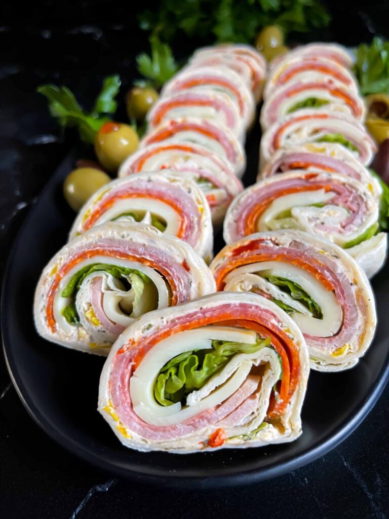 Italian pinwheels on a dark plate on a dark surface.