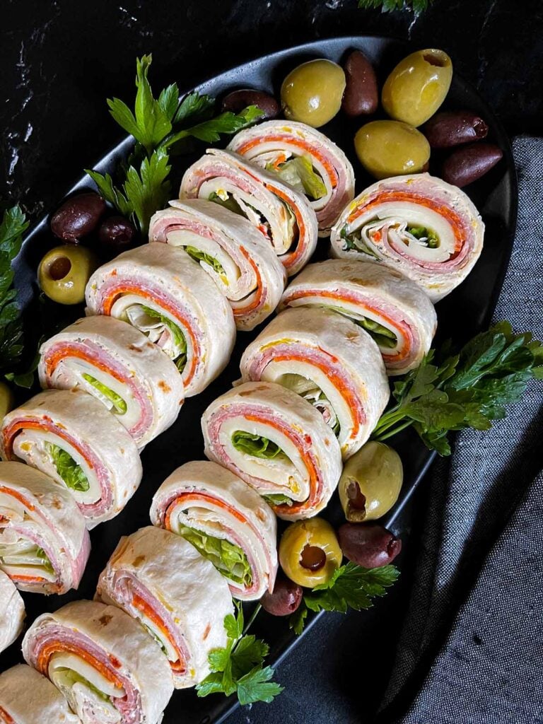 Italian pinwheels on a dark plate on a dark surface.