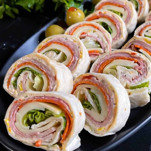 Italian pinwheels on a dark plate on a dark surface.