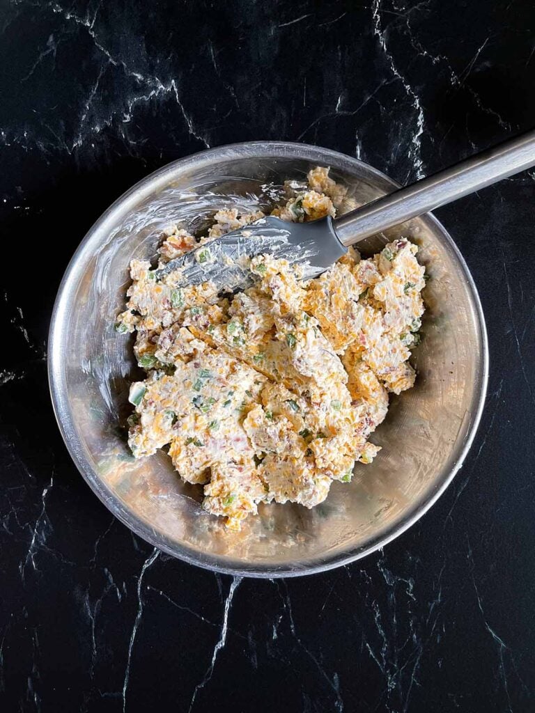 Jalapeno popper pinwheel ingredients mixed together in a metal mixing bowl.