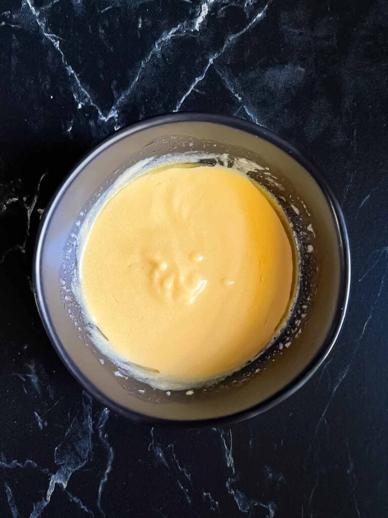 Dijon mustard sauce in a dark bowl.