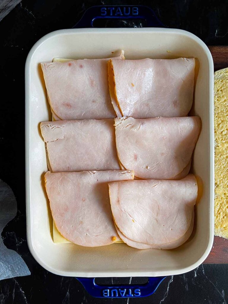 Turkey layered over slider rolls in a baking dish.