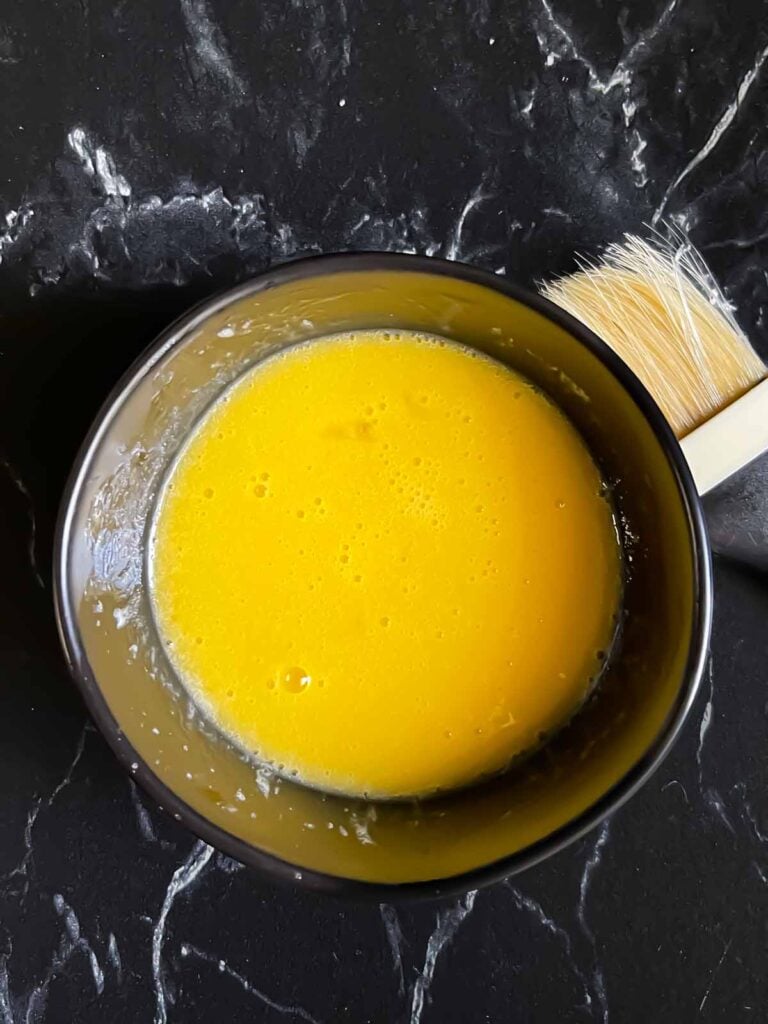 Egg wash in a dark bowl.