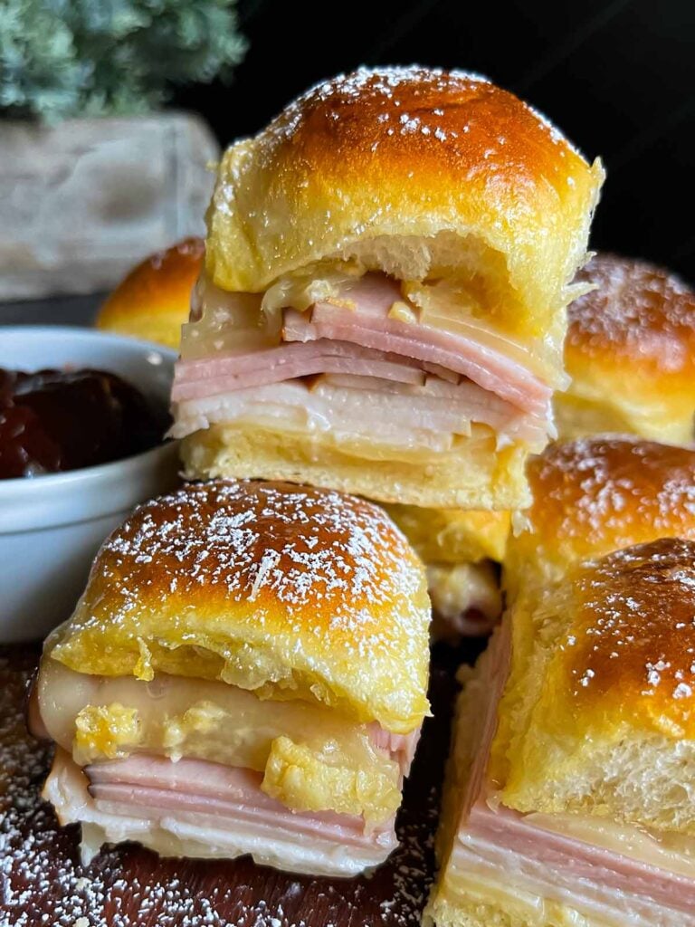 Monte Cristo sliders stacked up on a dark cutting board.