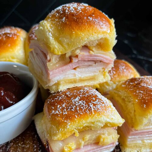 Monte Cristo sliders stacked up on a dark cutting board.