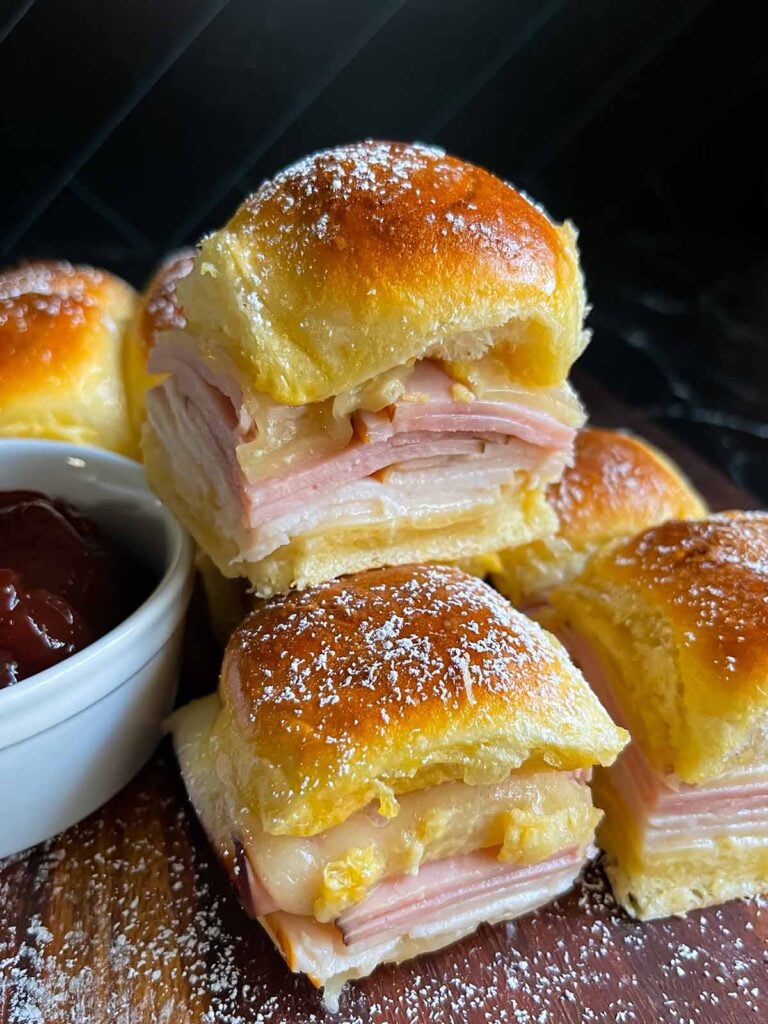 Monte Cristo sliders stacked up on a dark cutting board.