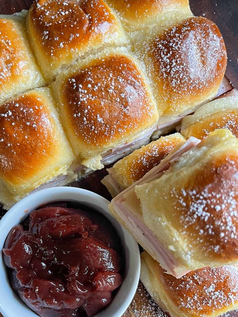 Monte Cristo sliders stacked up on a dark cutting board.