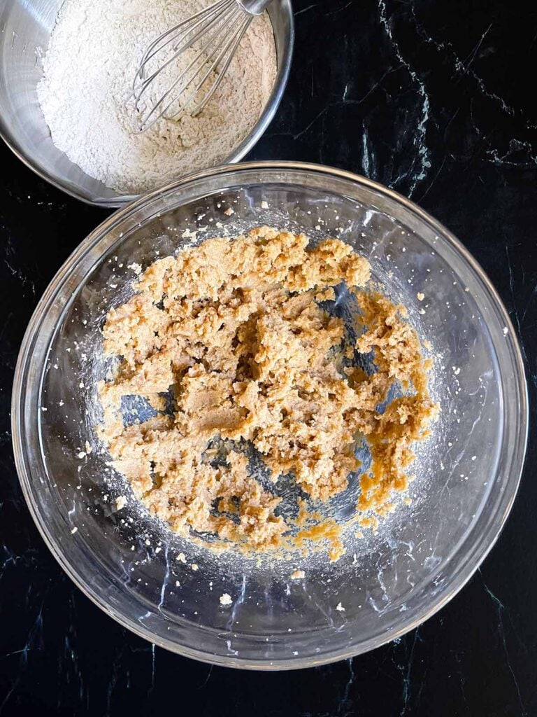 Butter and sugars creamed together for old fashioned oatmeal raisin cookies in a glass bowl.