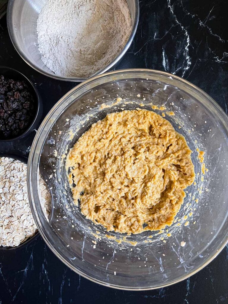 Creamed ingredients for oatmeal raisin cookies being mixed in a glass bowl.