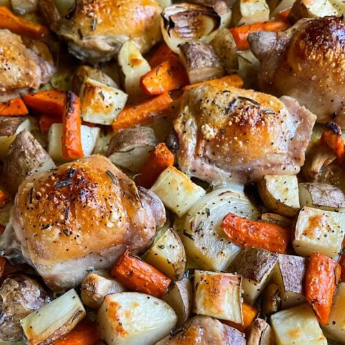 One pan roasted chicken and vegetables in a foil and parchment paper lined baking sheet.