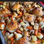 One pan roasted chicken and vegetables in a foil and parchment paper lined baking sheet.