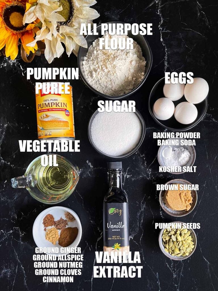 Ingredients for pumpkin bread on a dark surface.