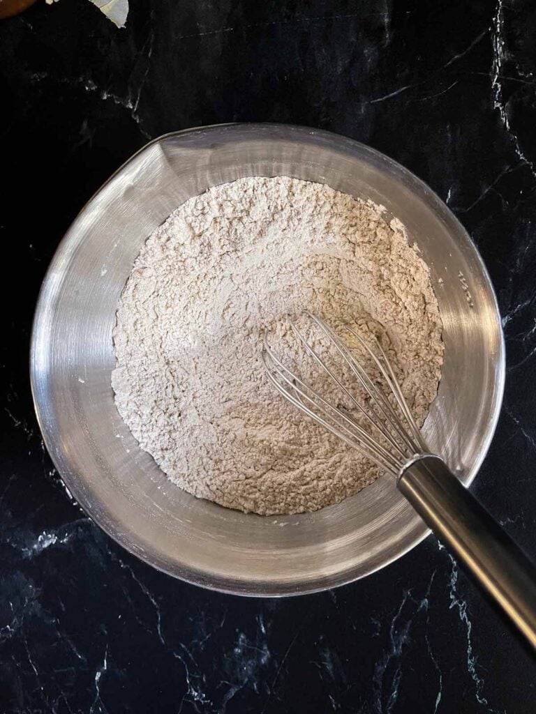 Combined dry ingredients for pumpkin bread in a mixing bowl.