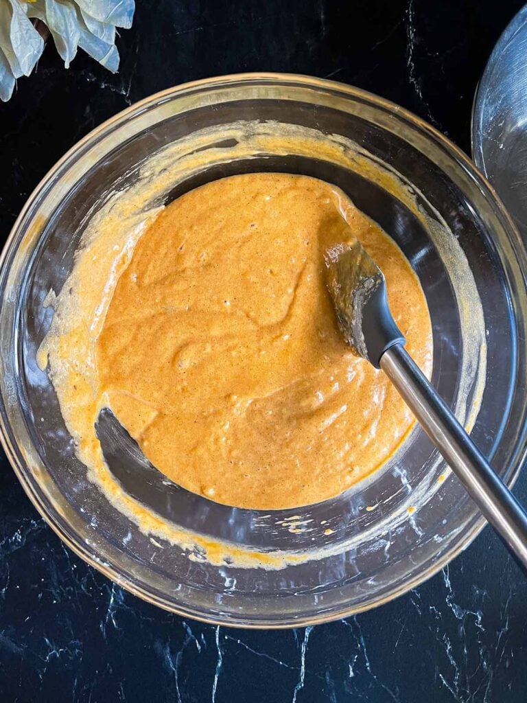 Pumpkin bread batter mixed together in a glass bowl.