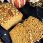 Baked pumpkin bread, sliced, on a dark platter.