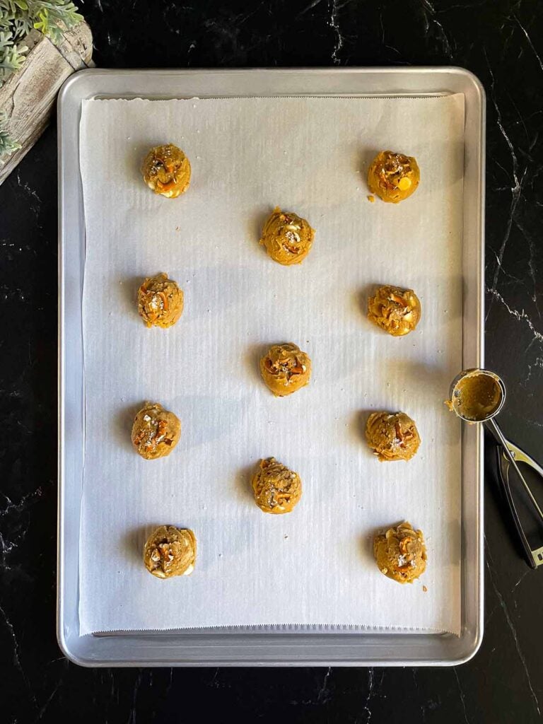 Salted Butterscotch Pretzel Cookie dough balls on a parchment paper lined baking sheet.