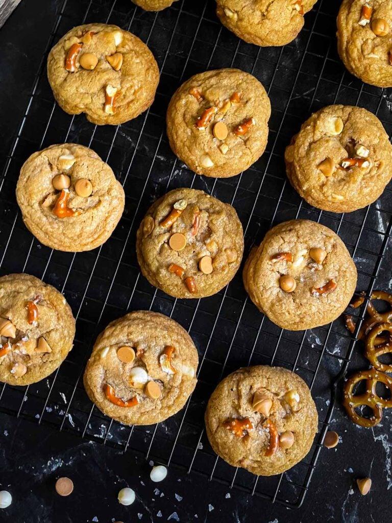 Salted Butterscotch Pretzel Cookies on a cooling rack on a dark surface.