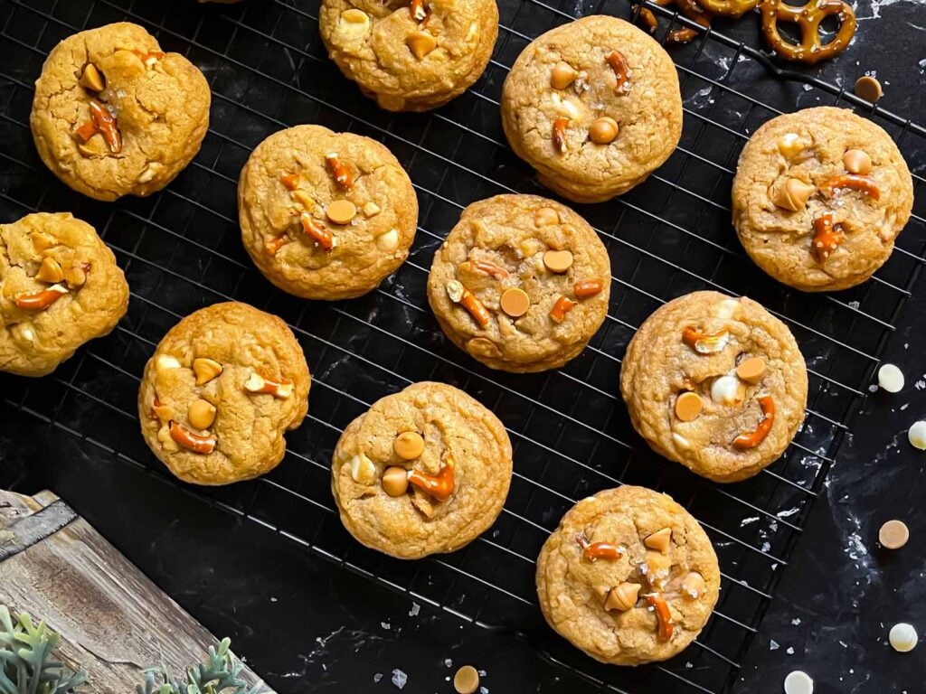 Salted Butterscotch Pretzel Cookies on a cooling rack on a dark surface.