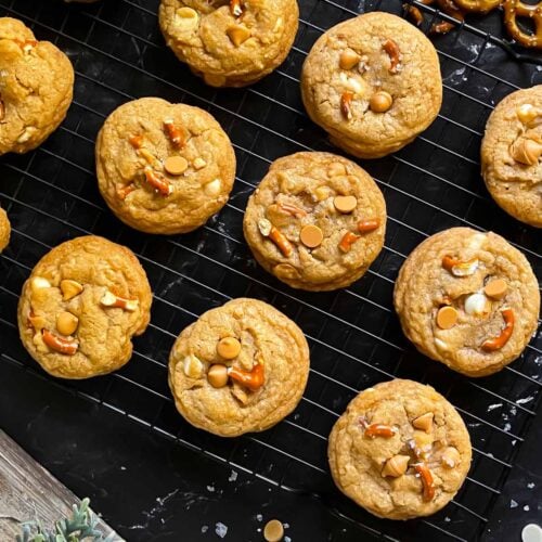 Salted Butterscotch Pretzel Cookies on a cooling rack on a dark surface.