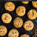 Salted Butterscotch Pretzel Cookies on a cooling rack on a dark surface.